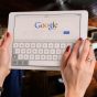 爱乃娜美资讯站资料研究员周岩的工作照，她手持平板电脑查阅日文资料，表情认真，背景是贴满便利贴的白板，呈现出严谨的资料研究状态
